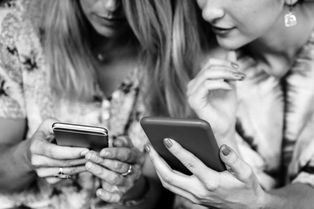 Due donne che leggono sul smartphone per confermare il buon contenuto serve sempre e dappertutto. Foto: Unsplash x simply walter